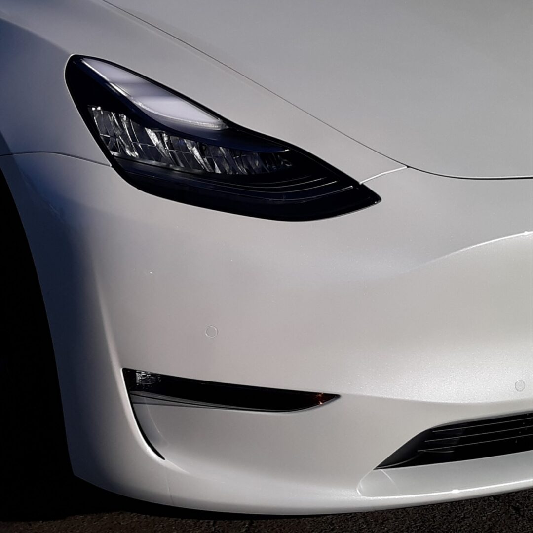 A close up of the front end of a white car.