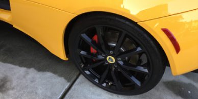 A yellow car with black rims and red brake calipers.